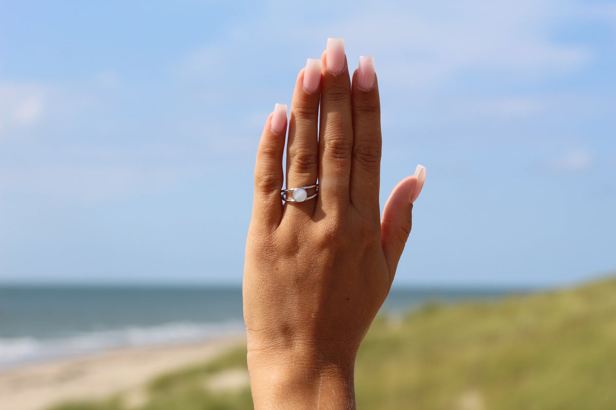 Massief witgouden ring met een heldere moedermelkhars en een elegante, moderne vorm, gedragen op een hand met lange, verzorgde nagels.