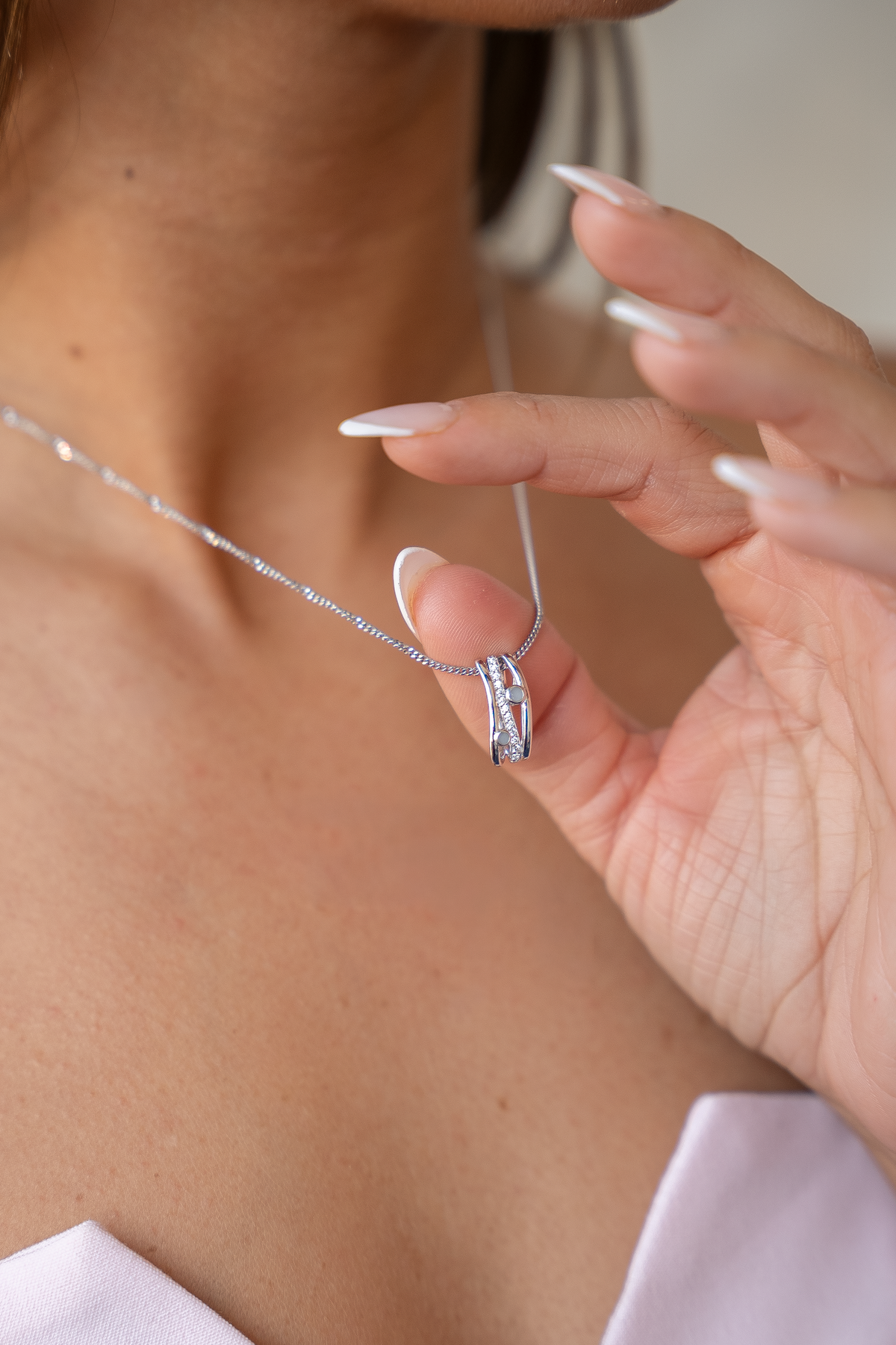 Hanger van 925 zilver met een glanzend oppervlak, zichtbaar moedermelkhars en een geboortesteen, vastgehouden door een persoon.