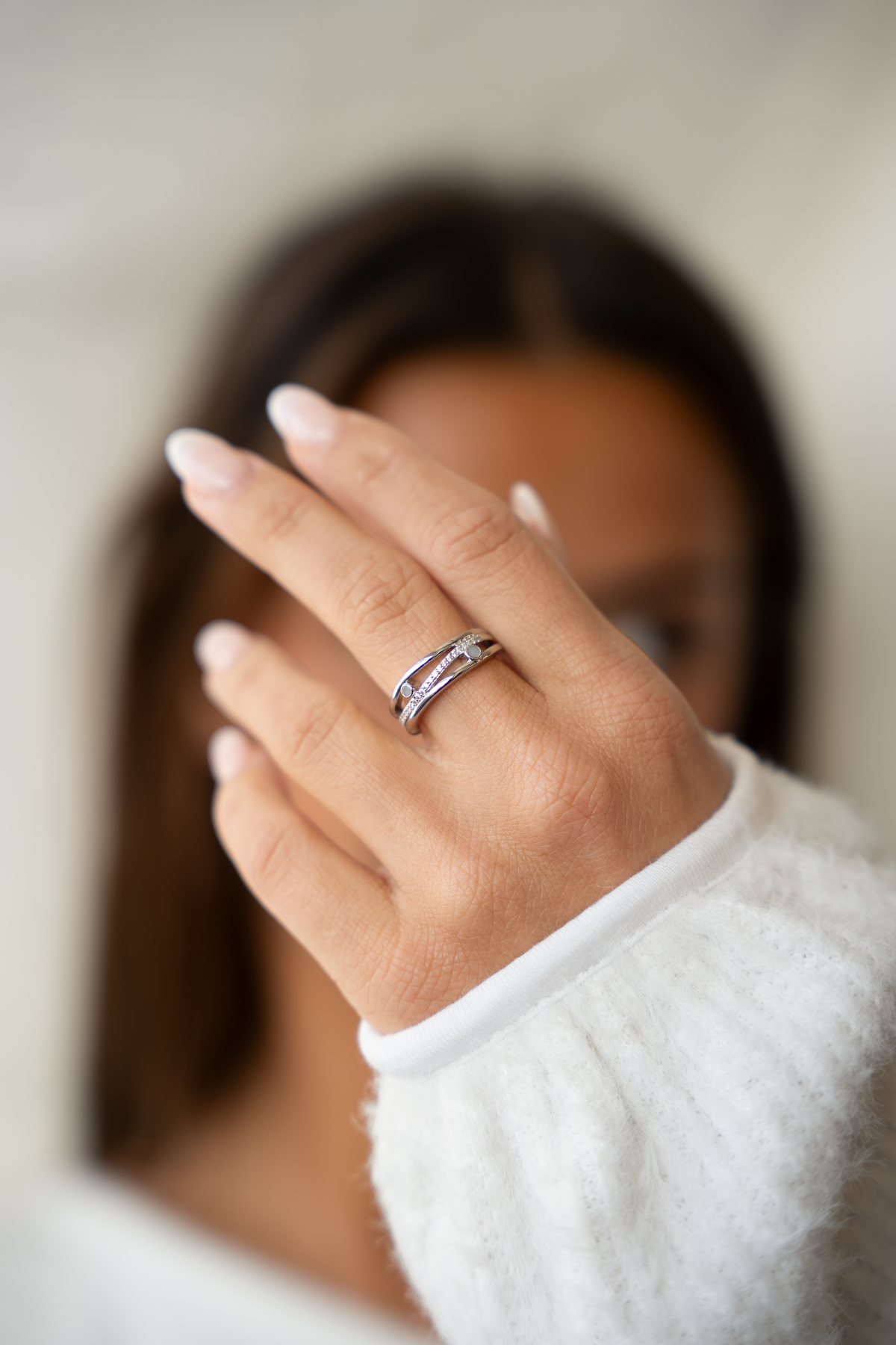 Massief witgouden ring met een elegante vorm, voorzien van een band van moedermelkhars en een geboortesteen, gedragen door een persoon.