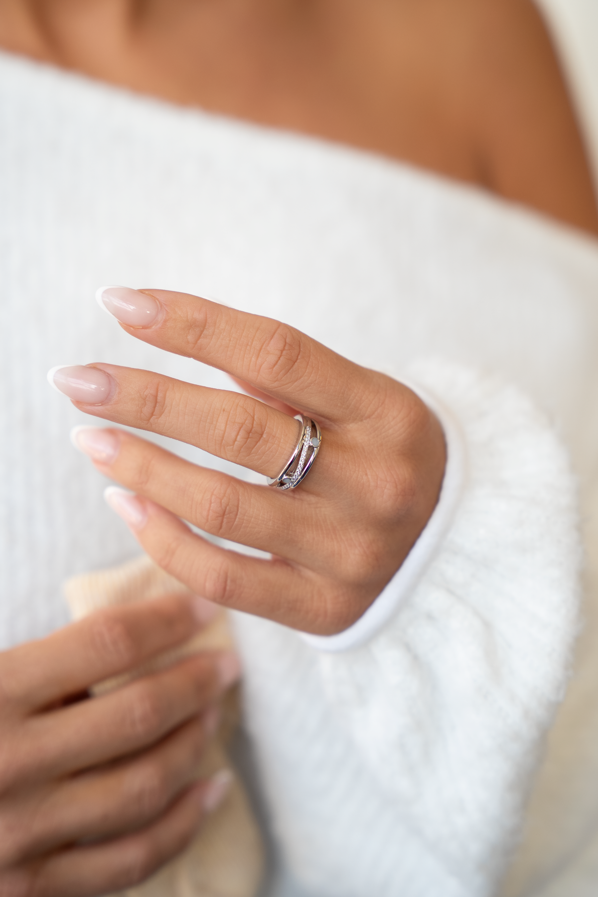 Massief witgouden ring met een gladde afwerking en een subtiele band, gedragen door een persoon met een witte trui.