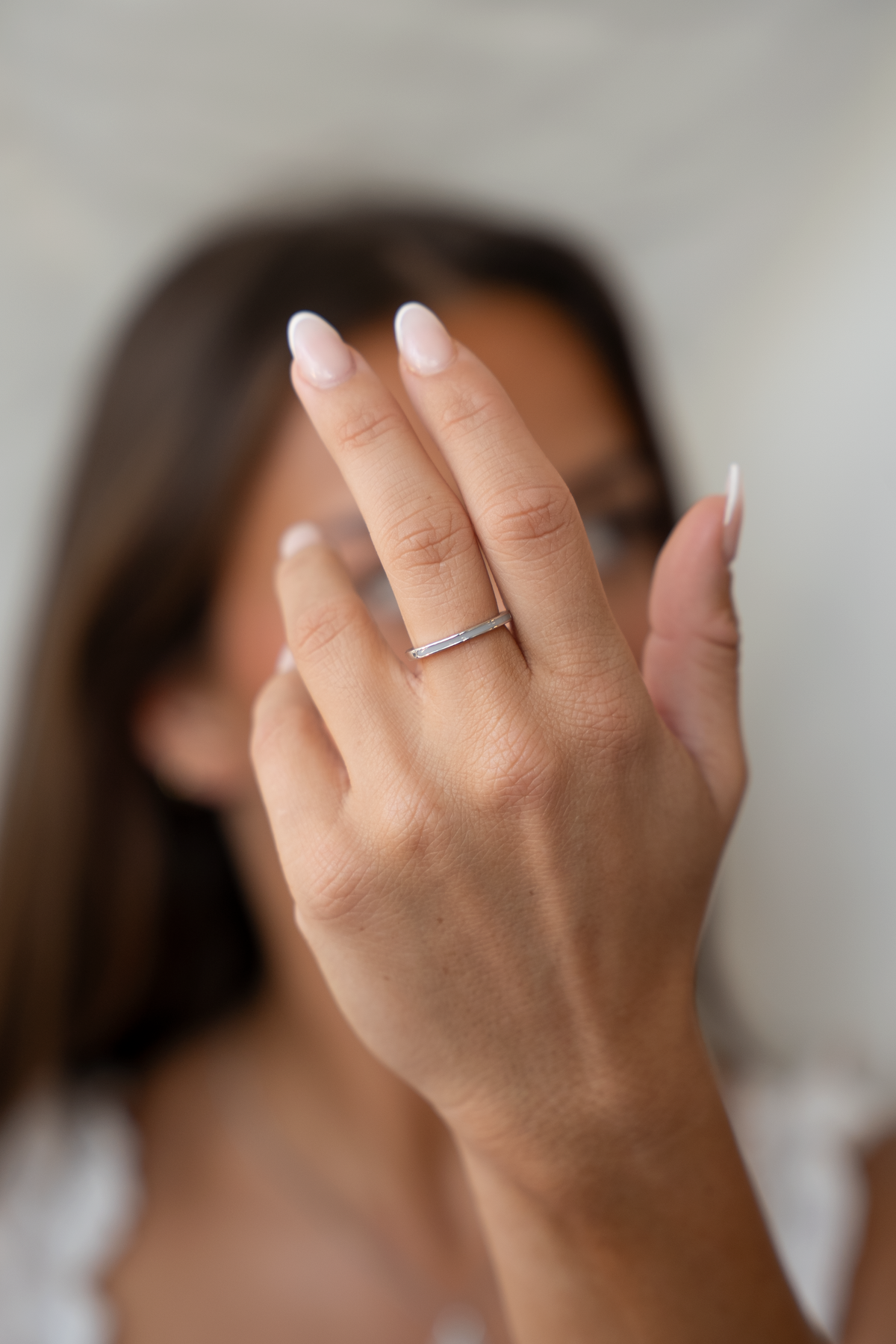 Verfijnde ring van massief witgoud met een strakke, moderne vorm, gedragen door een persoon met een natuurlijke manicure.