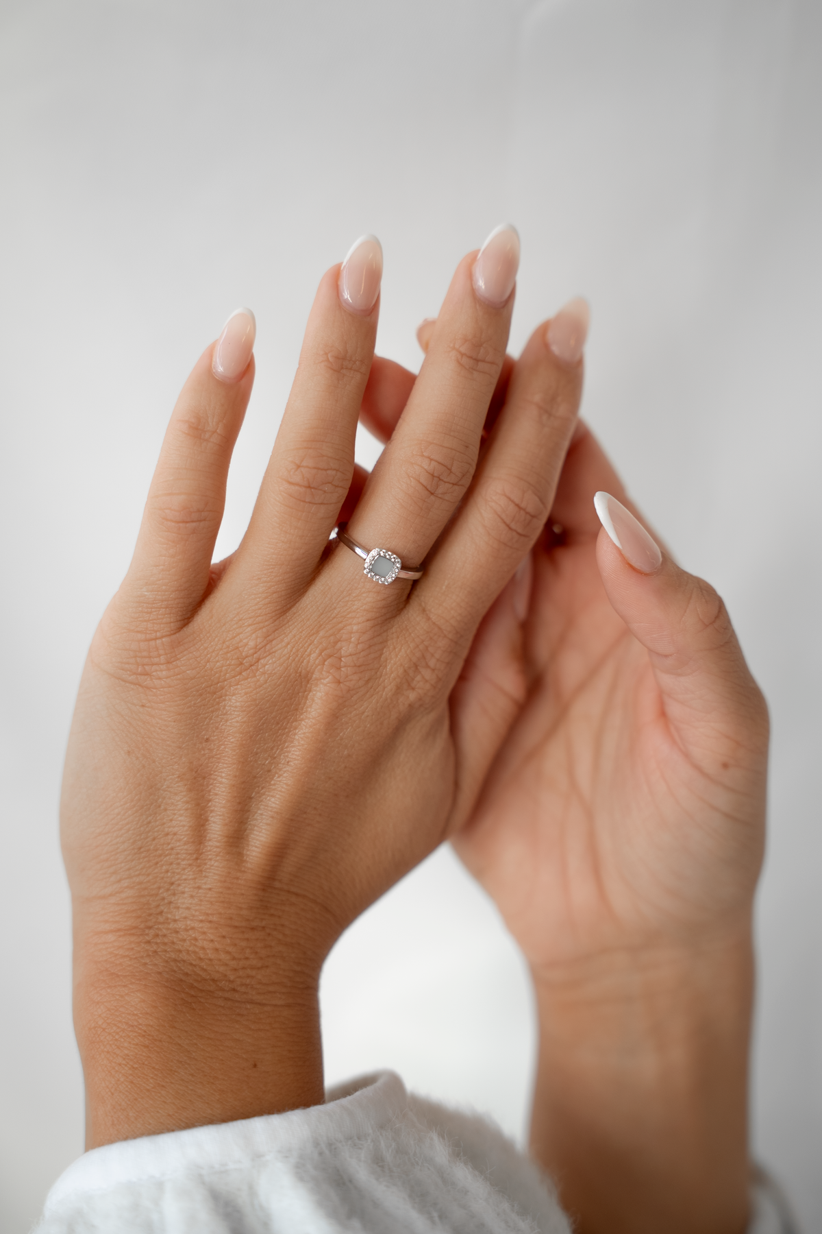 Ring van 925 zilver met een hartvormige moedermelkhars in het midden, gedragen op een hand met verzorgde nagels.