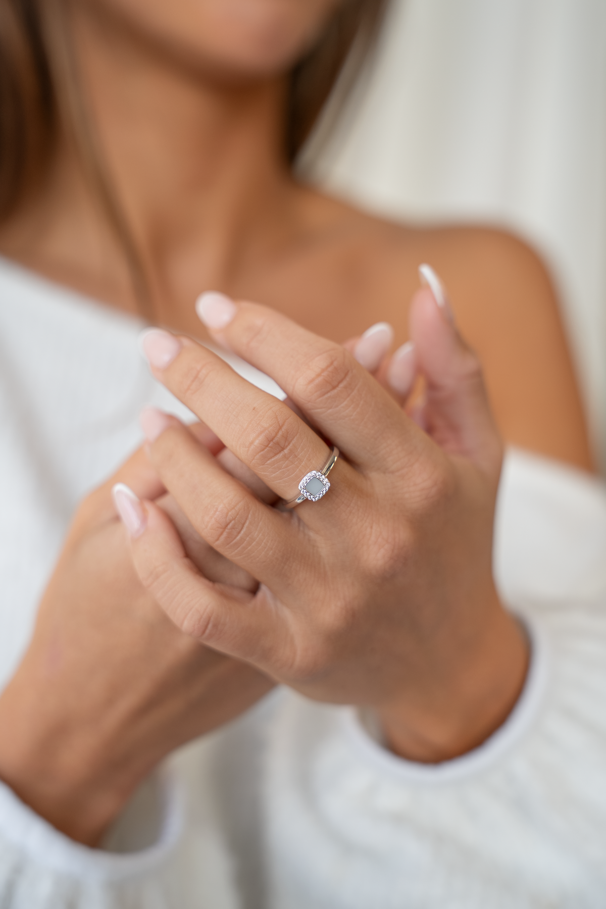 Moedermelkring van 925 zilver met een ovale, lichtblauwe steen, gedragen door een persoon met een lichte huid en verzorgde nagels.