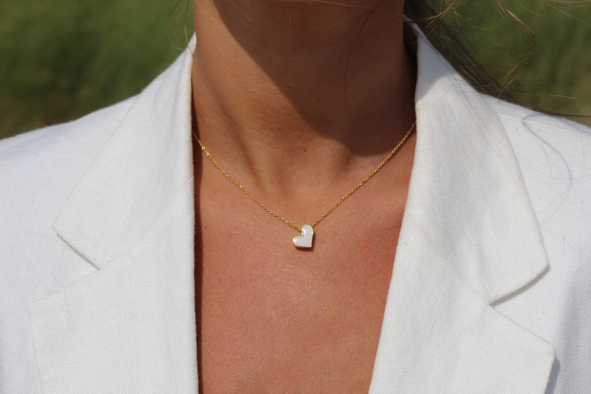 Hanger in geelgoud met een hartvormige schijf van moedermelkhars, gedragen aan een fijne ketting.