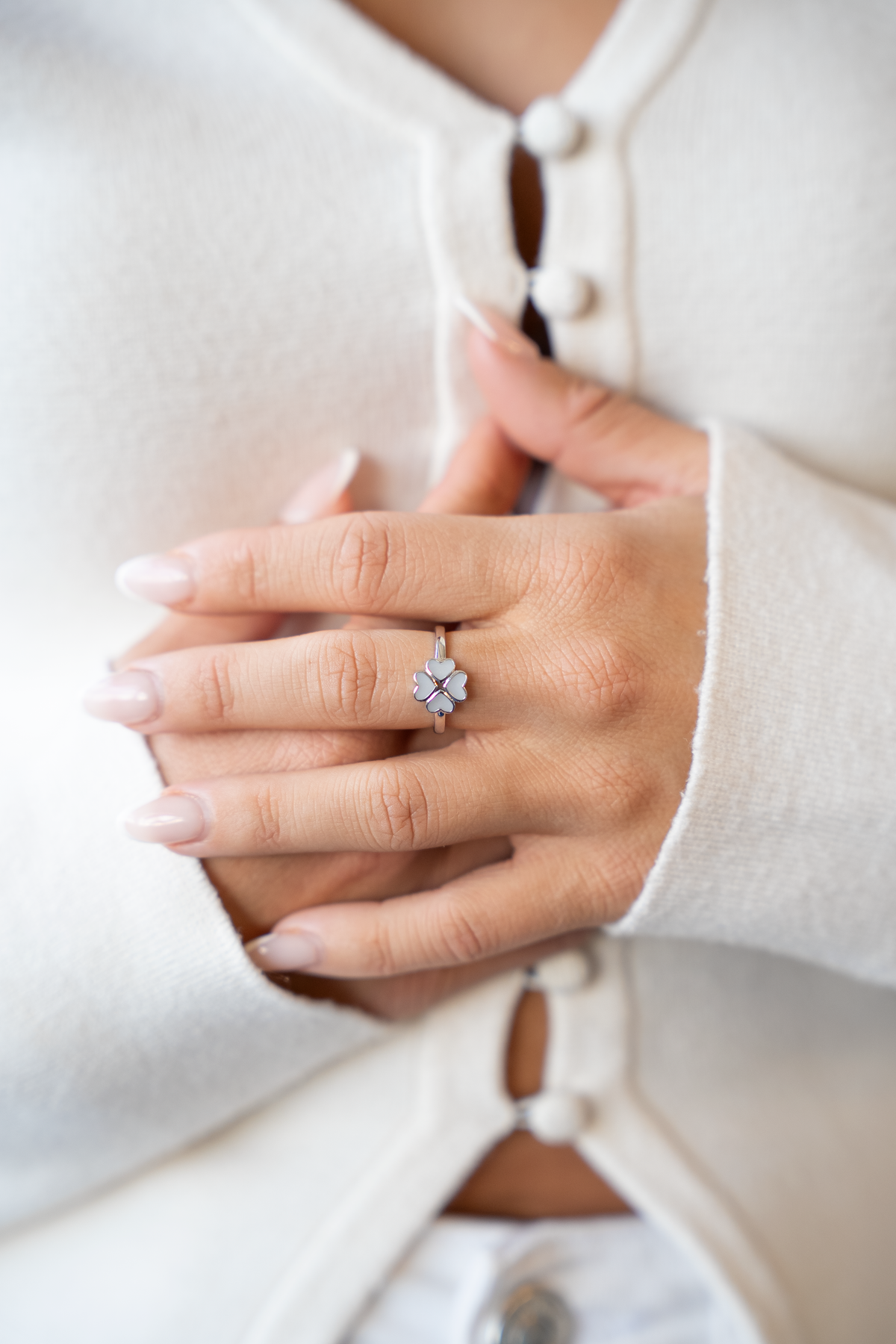 Massief witgouden ring met een bloemvormige zetting en een paarse geboortesteen, gedragen op een hand met lange nagels.