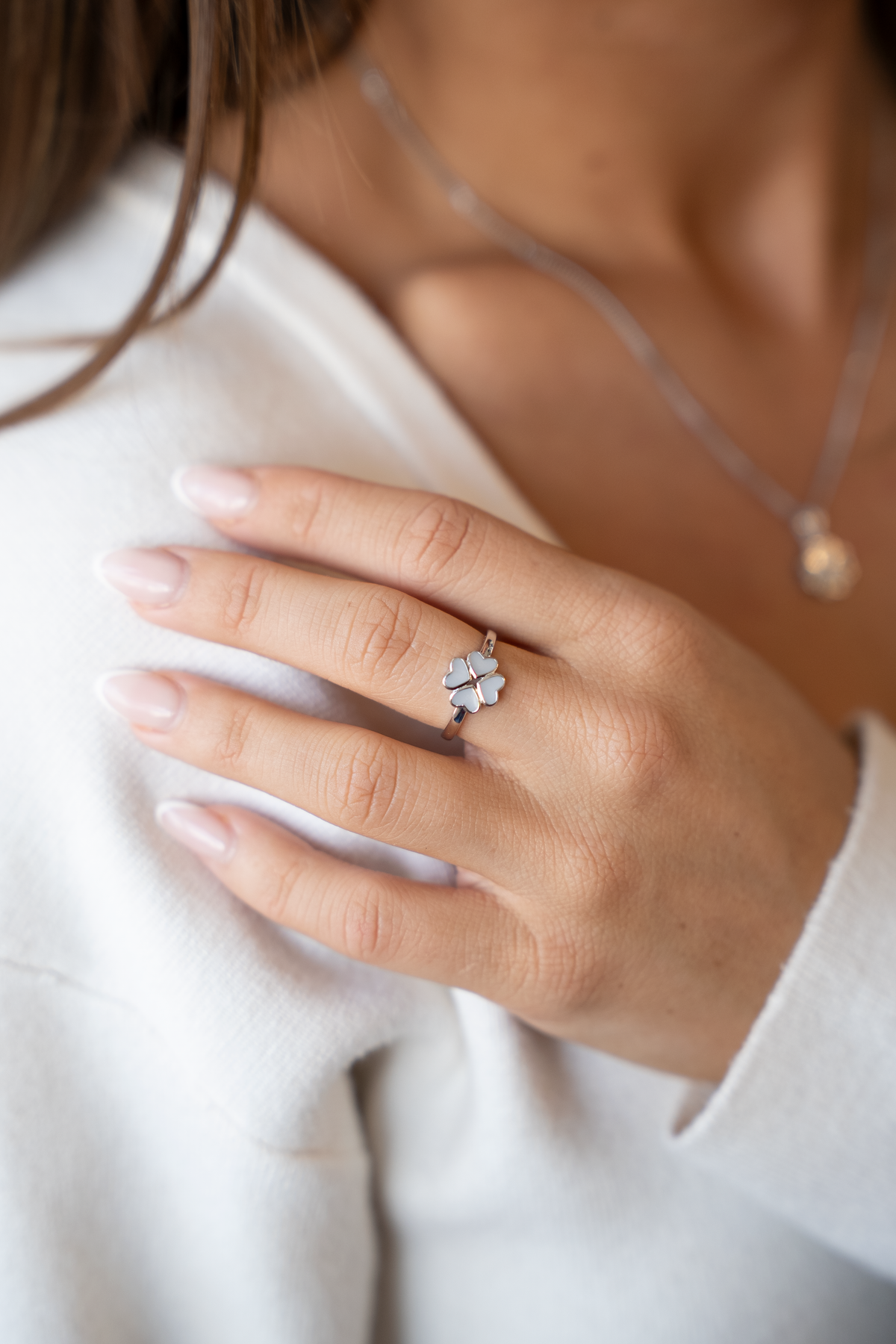 Massief witgouden ring met een schattige moedermelk-vorm en een subtiele afwerking, gedragen op een hand met verzorgde nagels.