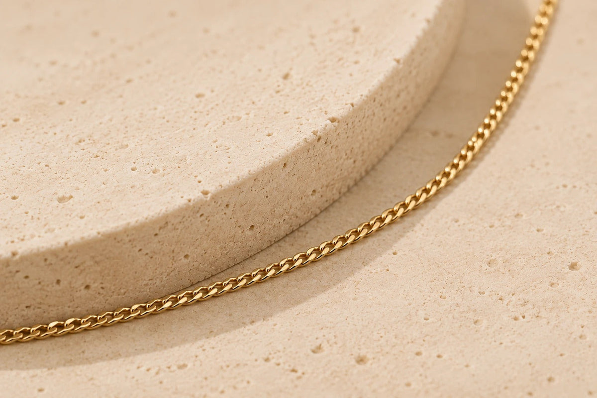 Fijne ketting van glanzend geel goud met sierlijke schakels op een neutrale ondergrond
