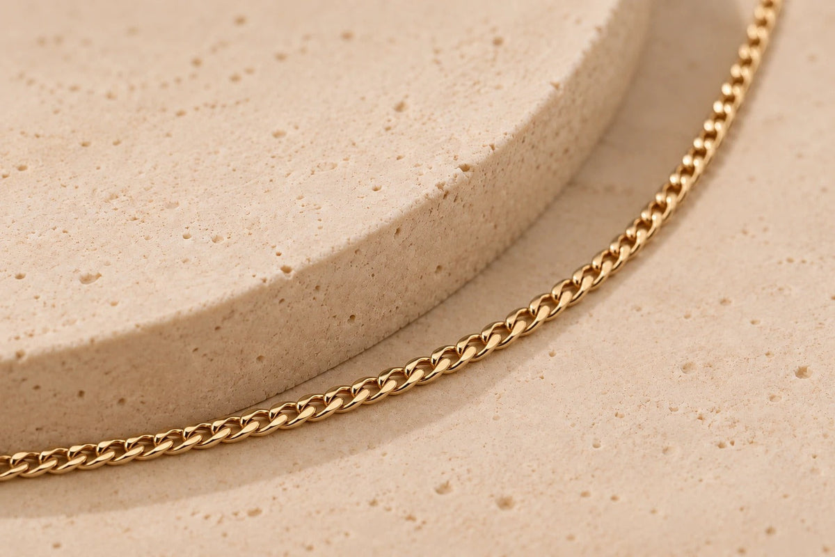 Ketting van geel goud gedrapeerd op een lichte, gestructureerde ondergrond
