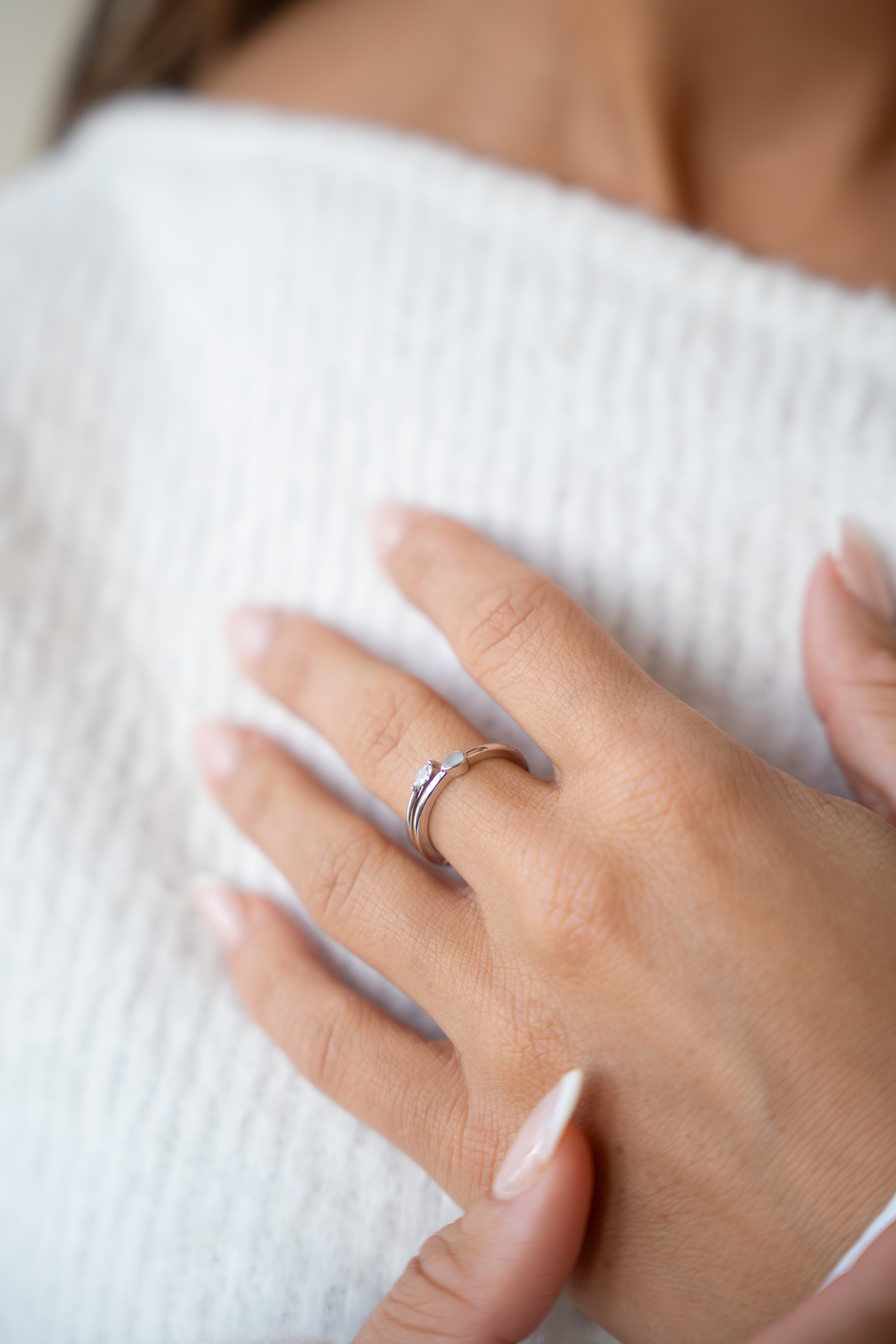 Massief witgouden ring met een elegante, minimalistische vorm en een inset van moedermelkhars, gedragen op een hand.