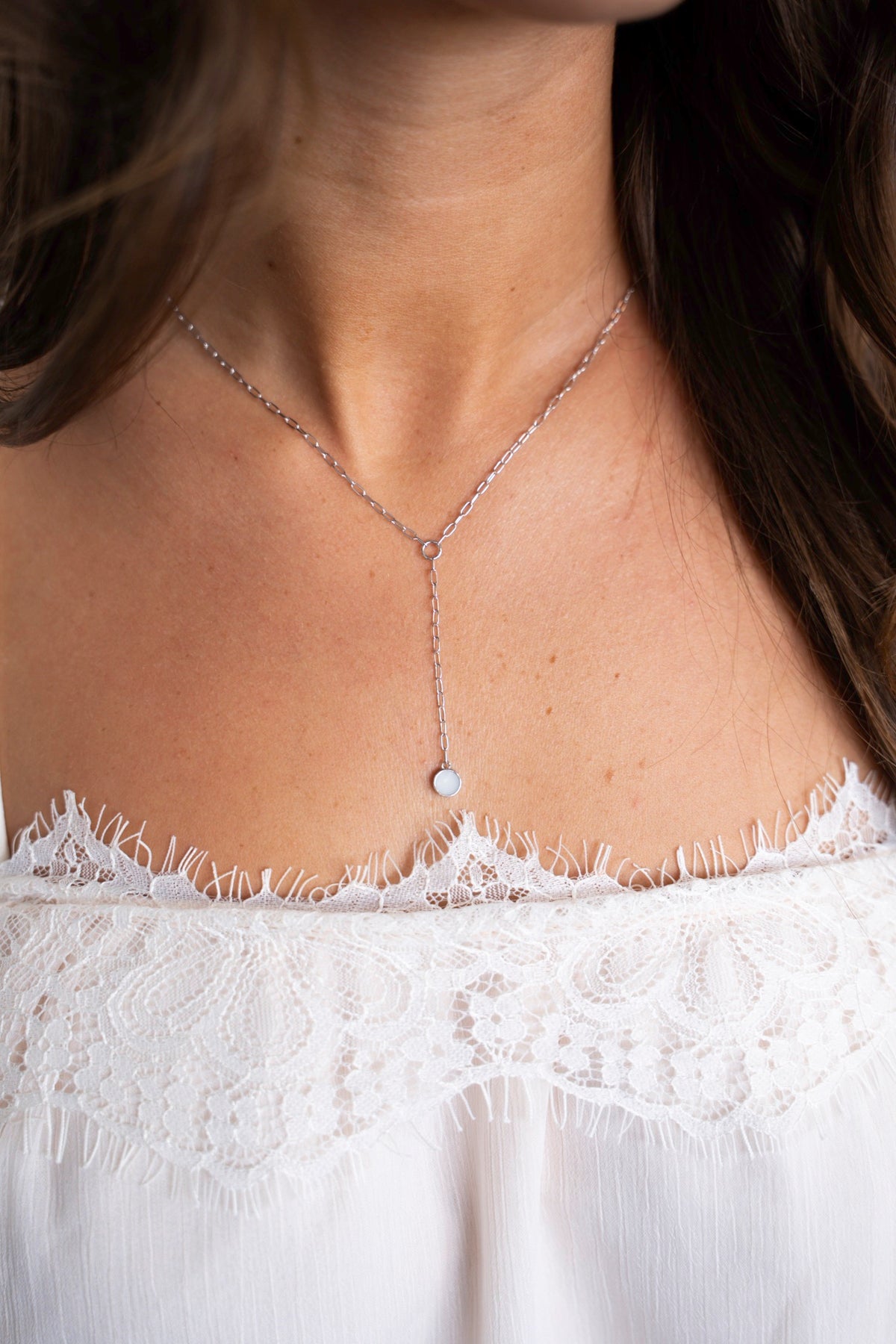 Close-up van de Norah Y-ketting van zilver met ronde moedermelksteen op het decolleté.