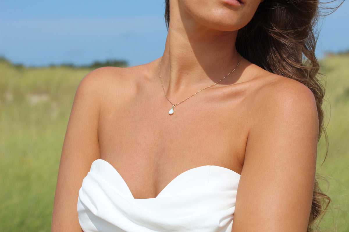 Hanger van 925 zilver in druppelvorm met een transparant moedermelkhars, gedragen door een vrouw met een strapless top.